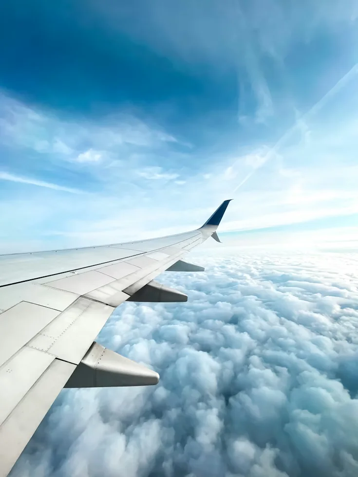 Airplane wing above the clouds, representing a travel savings goal